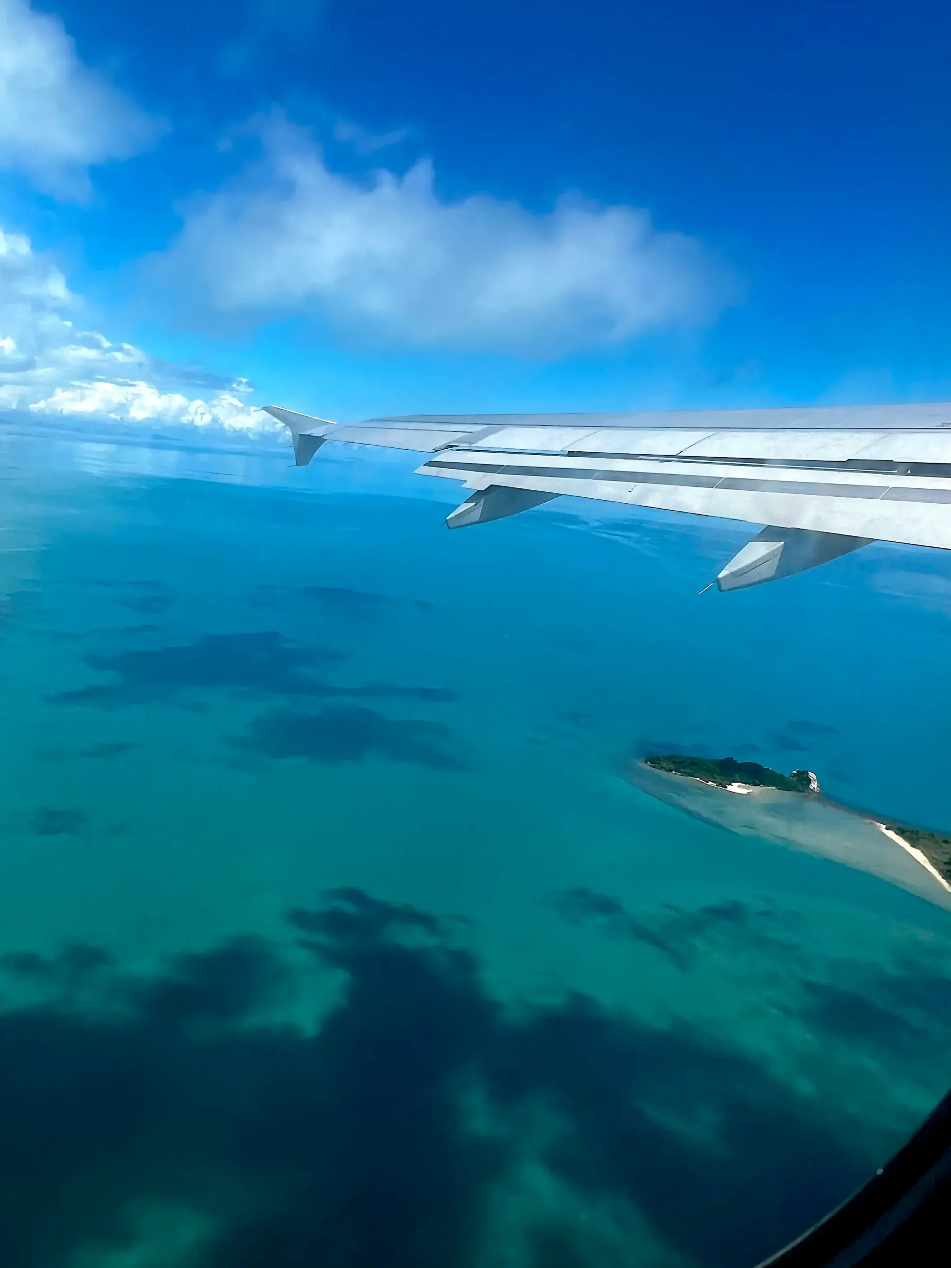 Blick aus dem Flugzeug auf eine kleine Insel im türkisblauen Meer – Reiseimpression von Immobilienmakler Nico Gutzeit